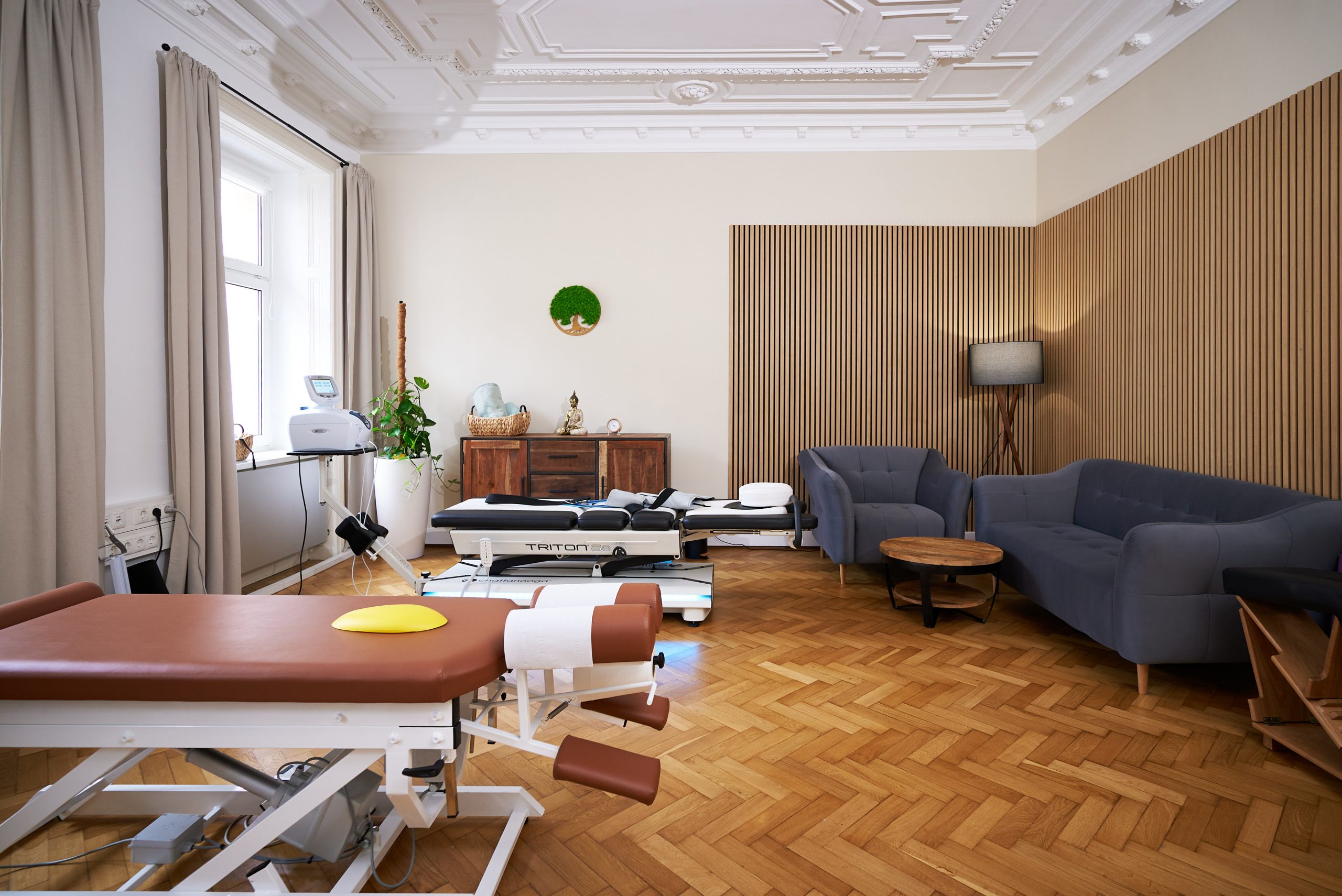 Der gemütliche und moderne Behandlungsraum im ChiroZentrum Wien mit einer Extensionsliege und einer Chiropraktik Liege.