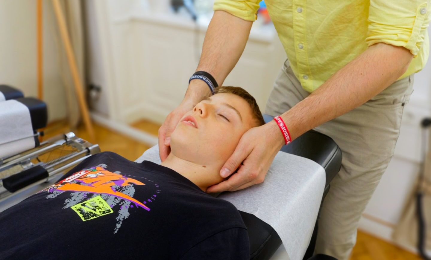 Chiropraktiker Marek Sukenik behandelt ein Kind durch Justierung am Kopf.