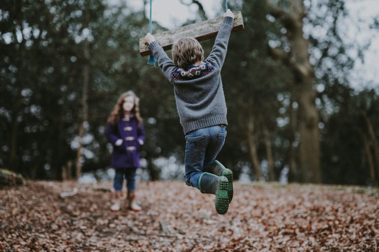 Kinder spielen auf einem Spielplatz mit einer Schaukel
